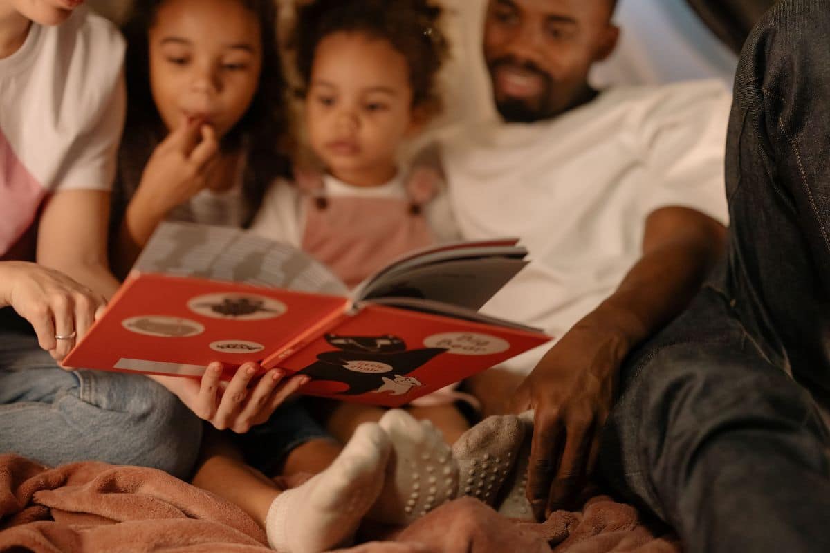 Família lendo um livro com duas crianças e conversando sobre a história
