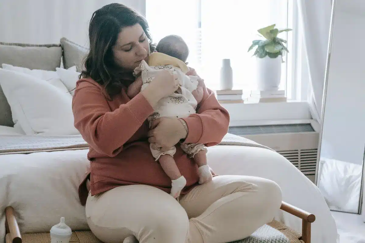 Mãe segurando o bebê no colo em um quarto claro
