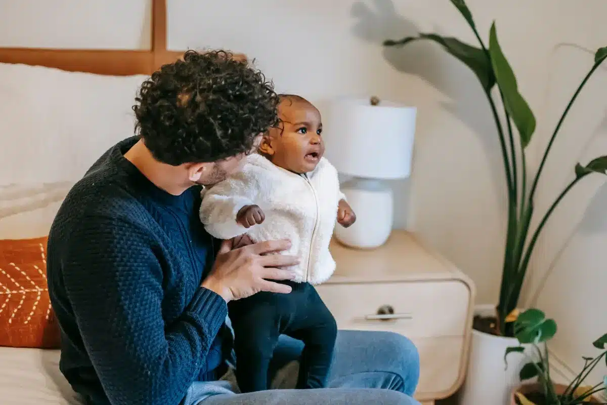 Pai segurando e acolhendo um bebê no quarto